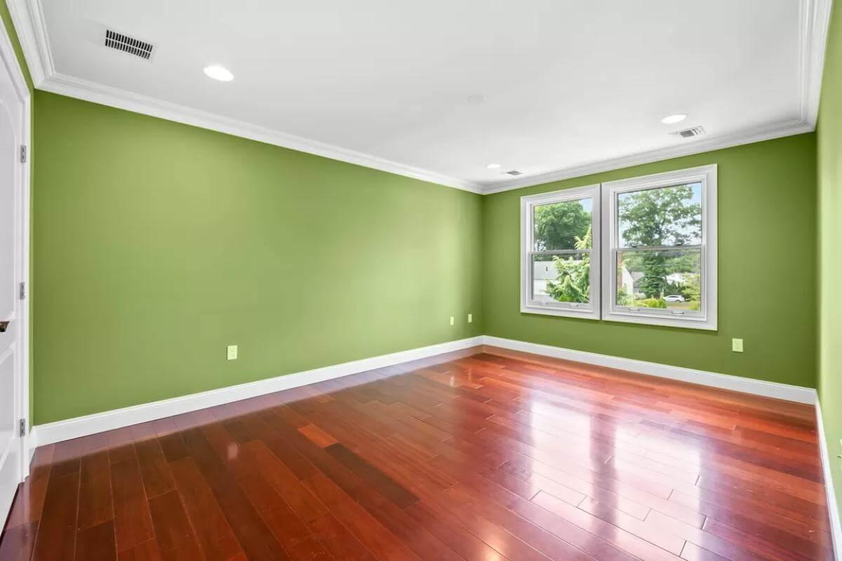 Take In the Bold Green Walls Complementing Rich Wooden Floors