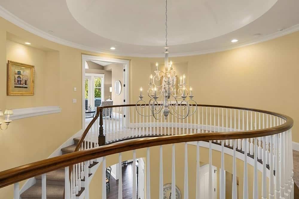Marvel at the Curved Railing and Elegant Chandelier Centerpiece