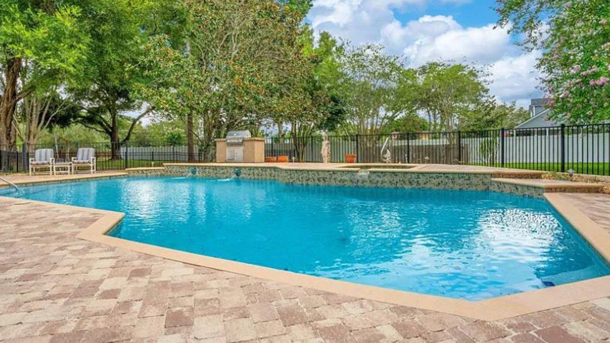 Notice the Outdoor Grill Setup Complementing This Poolside Haven
