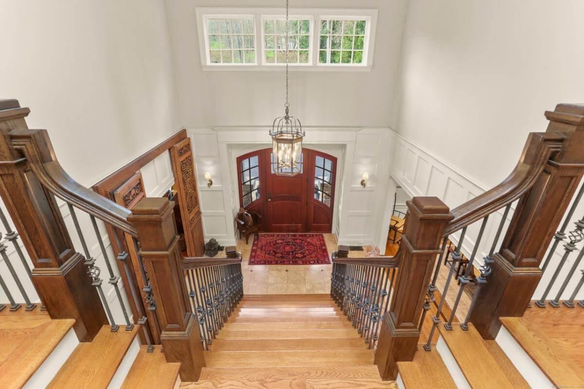 Grand Entrance with Classic Staircase and Welcoming Red Doors