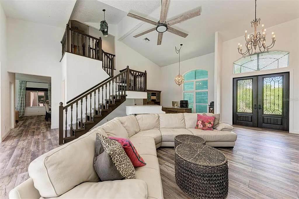 Spacious Living Area with Grand Ceiling Fan and Open Staircase