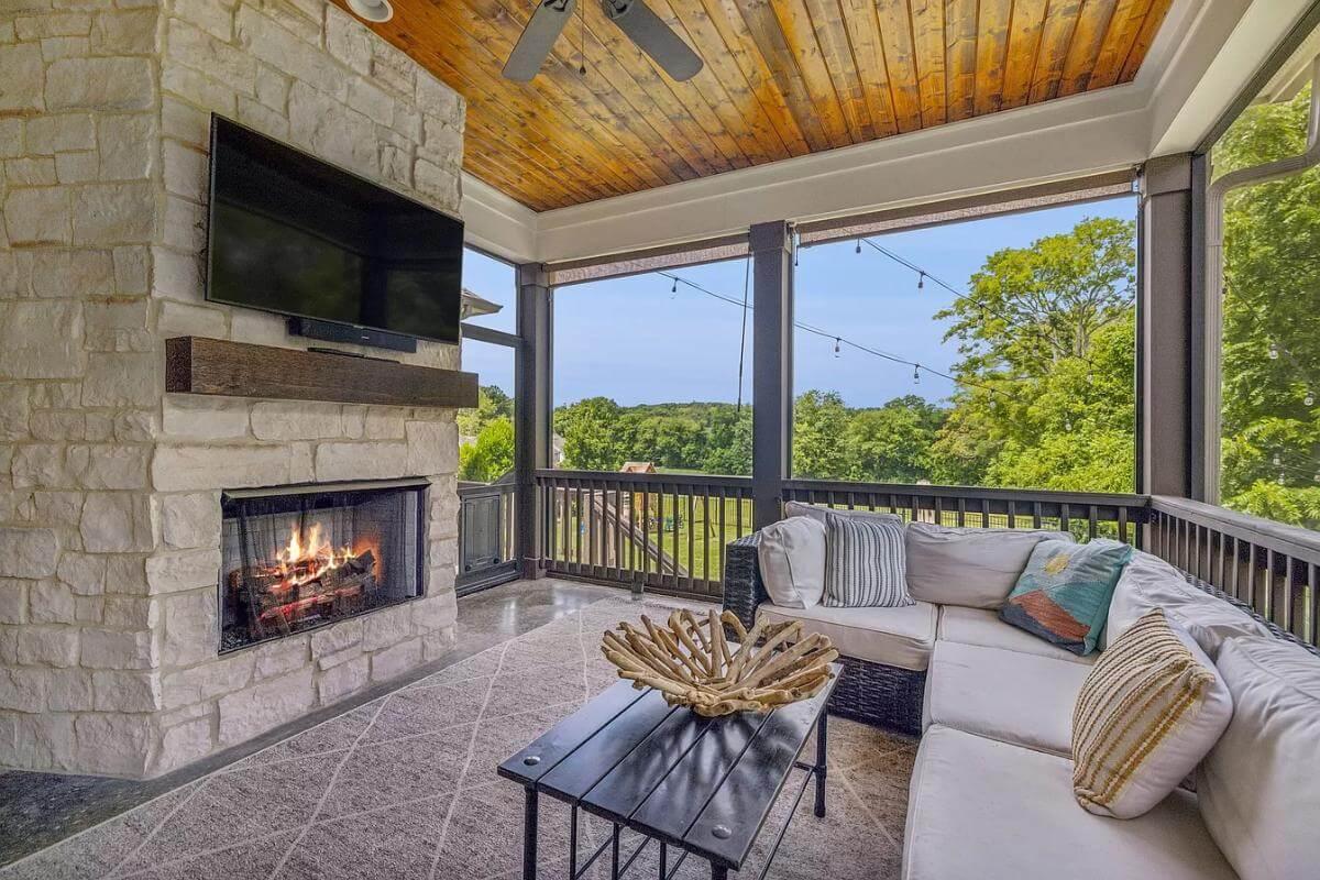 Relax in This Screened Porch with Stone Fireplace and Wood Ceiling