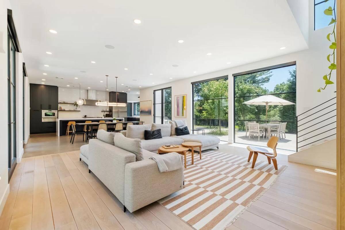 Open-Concept Living Room with Wall-to-Wall Windows Leading to Outdoor Dining