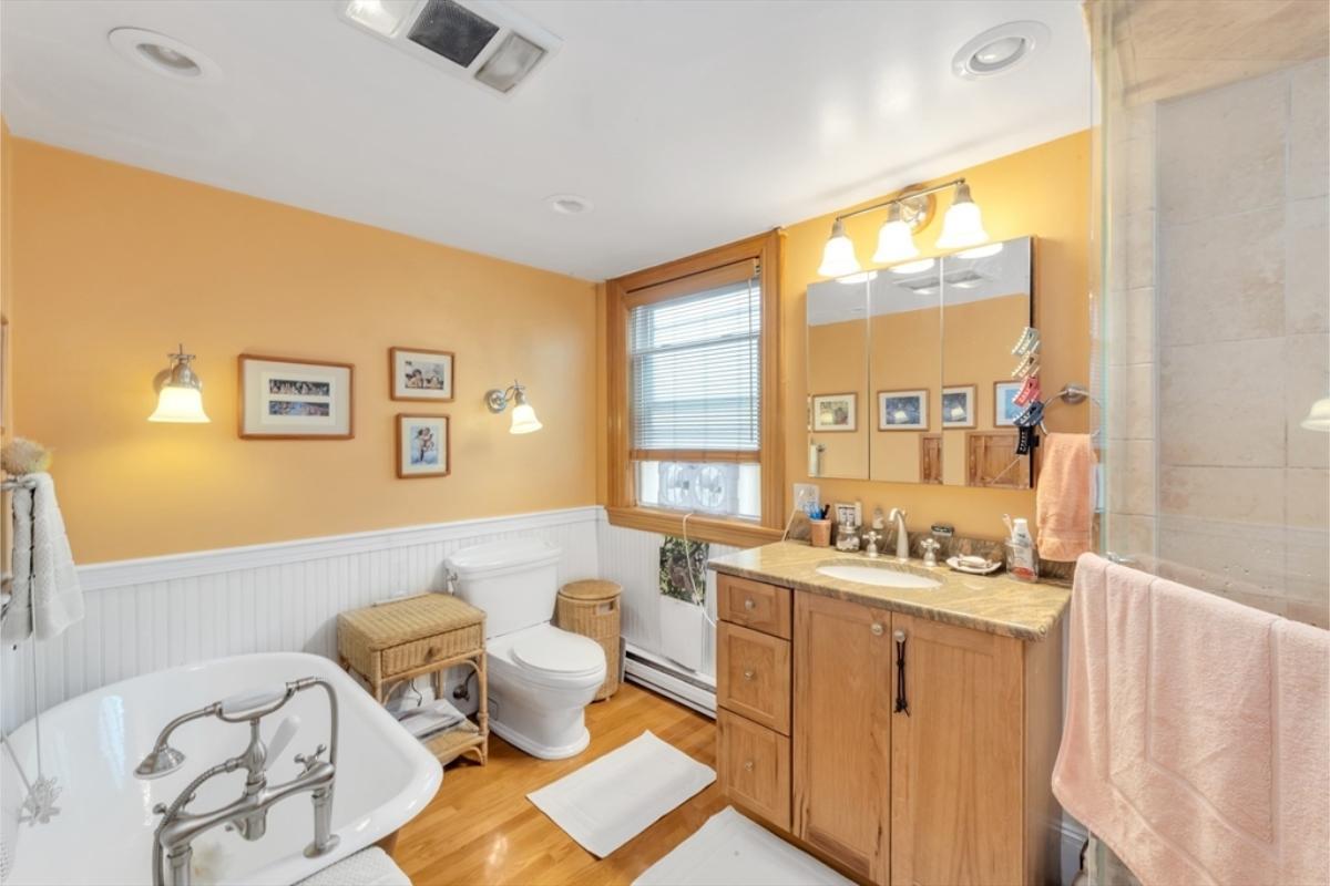 Sunny Bathroom with a Pedestal Tub and Beadboard Wainscoting