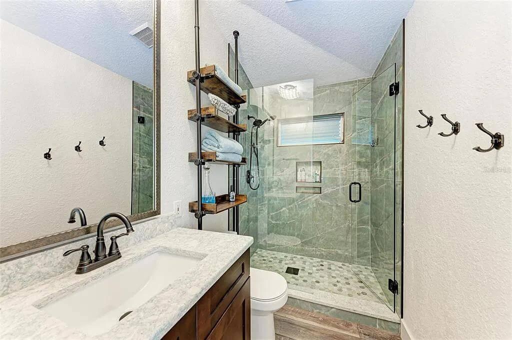 Compact Bathroom with Industrial Shelving and Glass Shower