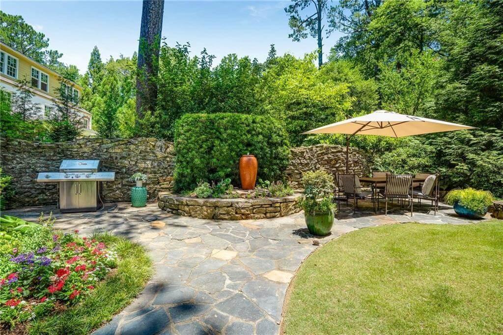 Discover the Stone Patio with Built-In Grill and Serene Garden Views