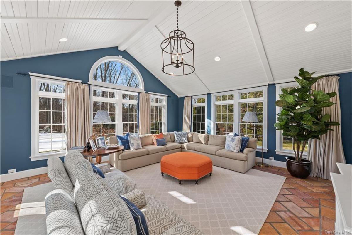 Sunlit Sunroom Highlighting Vaulted Ceilings and a Bold Orange Ottoman