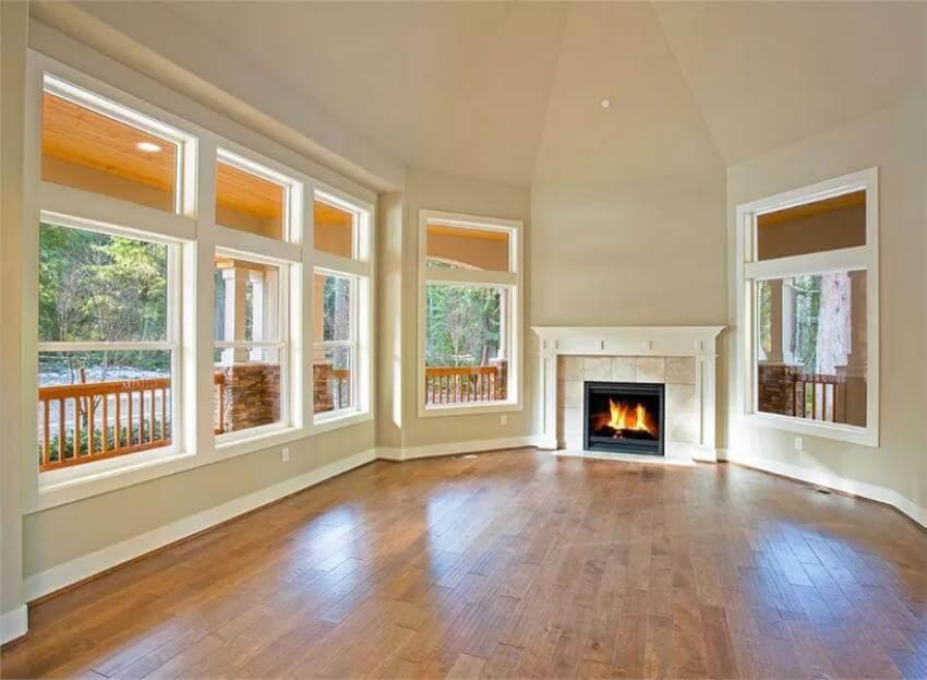Admire the Expansive Windows and Cozy Fireplace in This Living Room