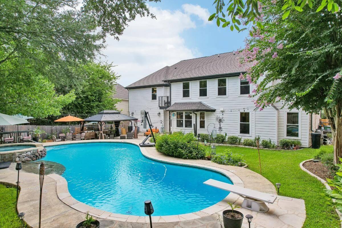Dive into Relaxation at This Backyard Pool with Cozy Gazebo and Lush Greenery