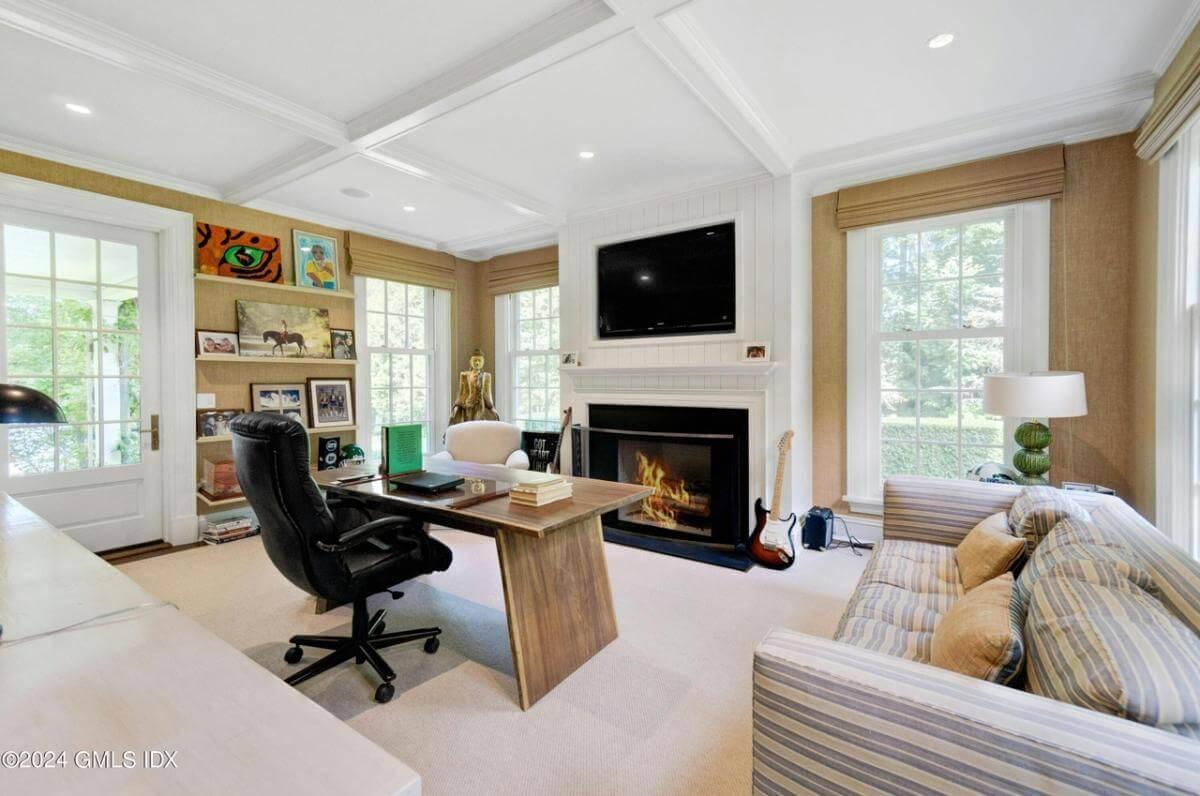 Notice the Cozy Home Office with a Fireplace and Portrait Wall