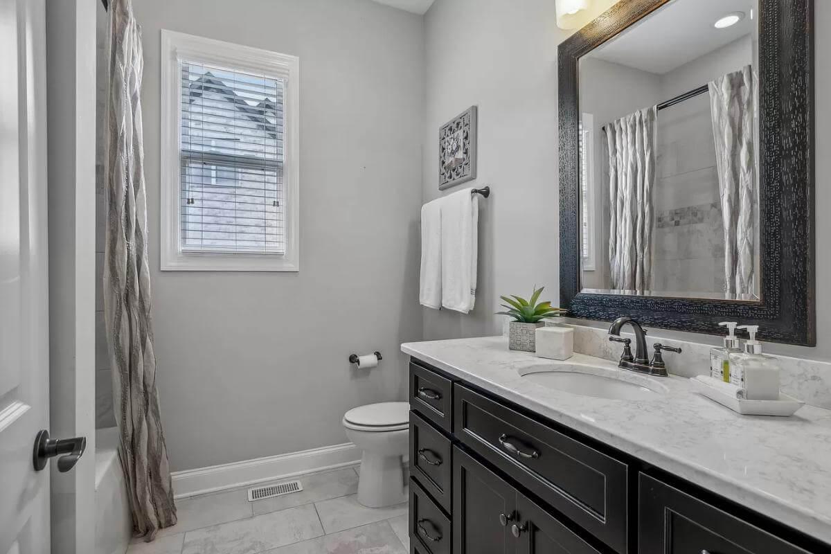 This Bathroom Shines with Its Dark Vanity and Crisp Marble Countertop