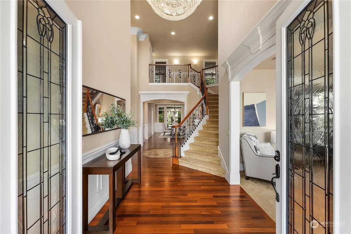 Admire the Grand Entryway with Its Stunning Chandelier and Warm Wood Floors