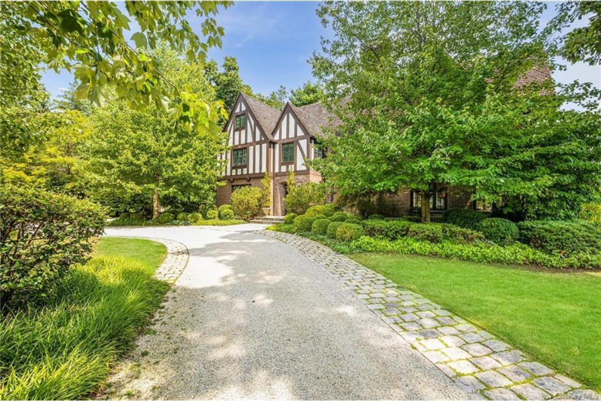 Tudor Revival with Lush Surroundings and Cobblestone Path – A Storybook Entrance