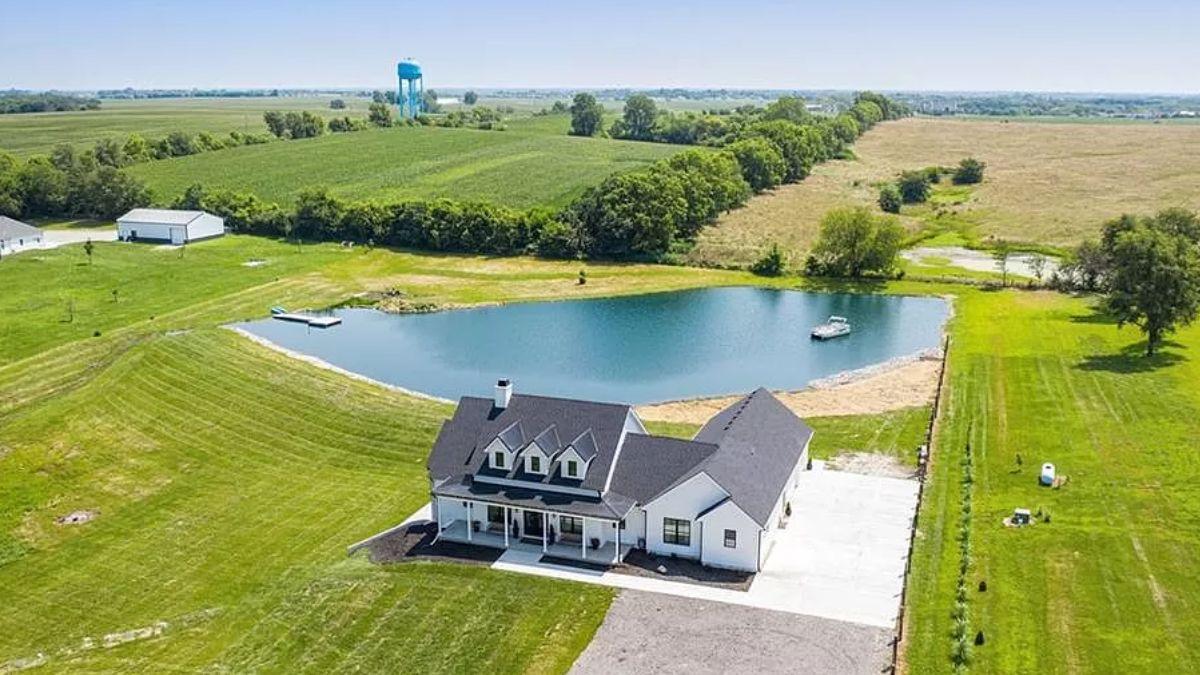 Aerial View of Farmhouse with Serene Pond and Expansive Fields