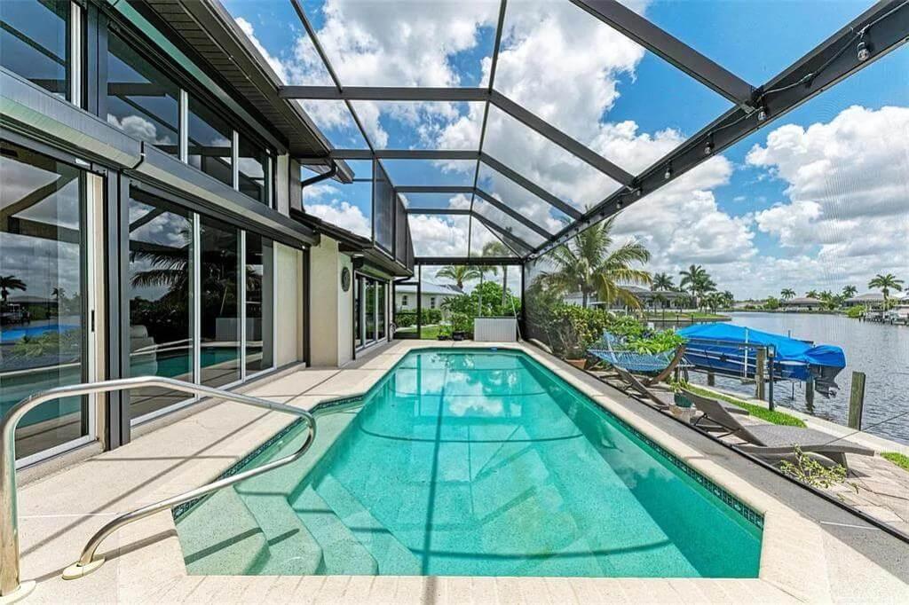 Expansive Pool Area with Enclosed Lanai and Waterfront Vistas