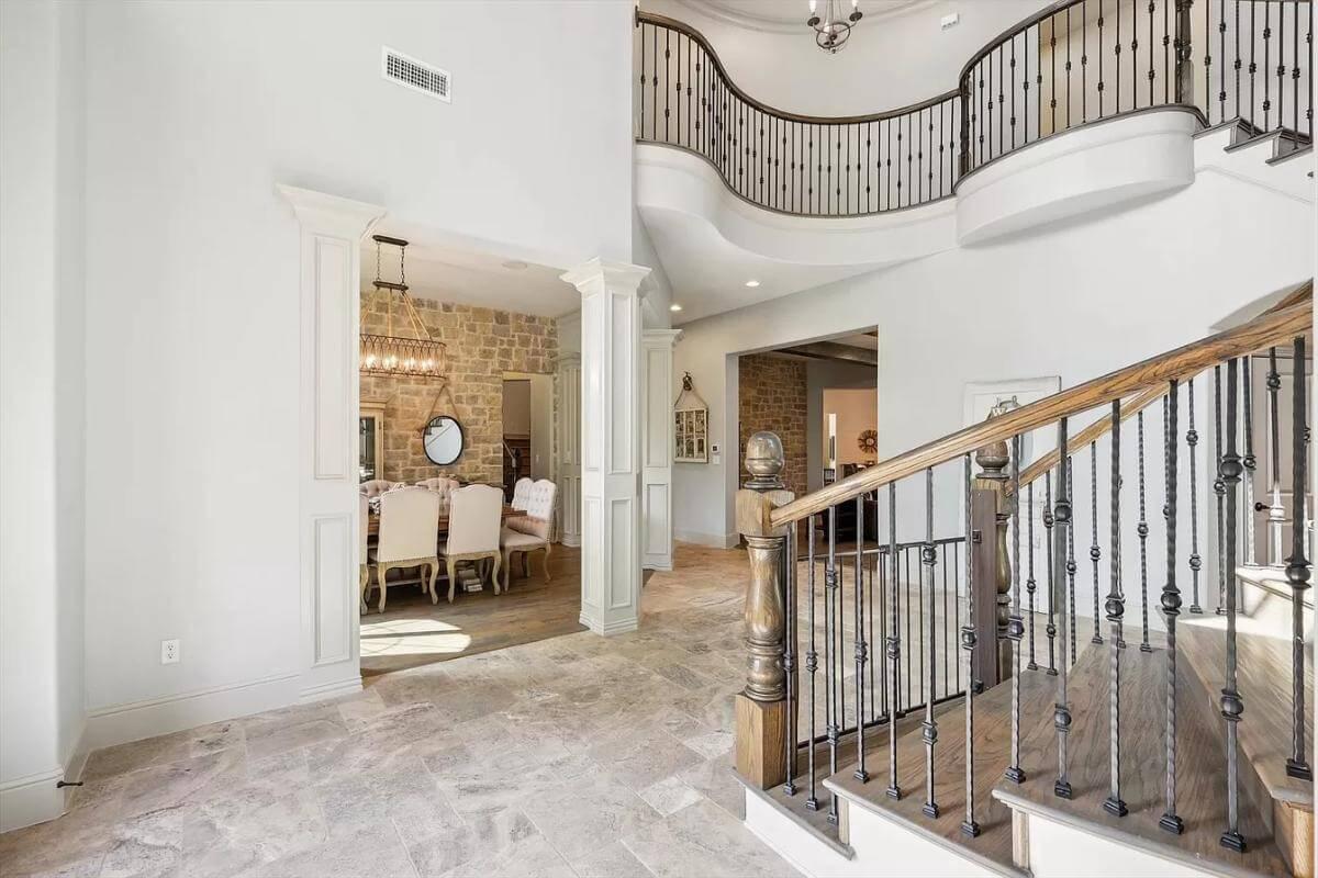 Elegant Foyer with Curved Balcony and Rustic Dining Touch