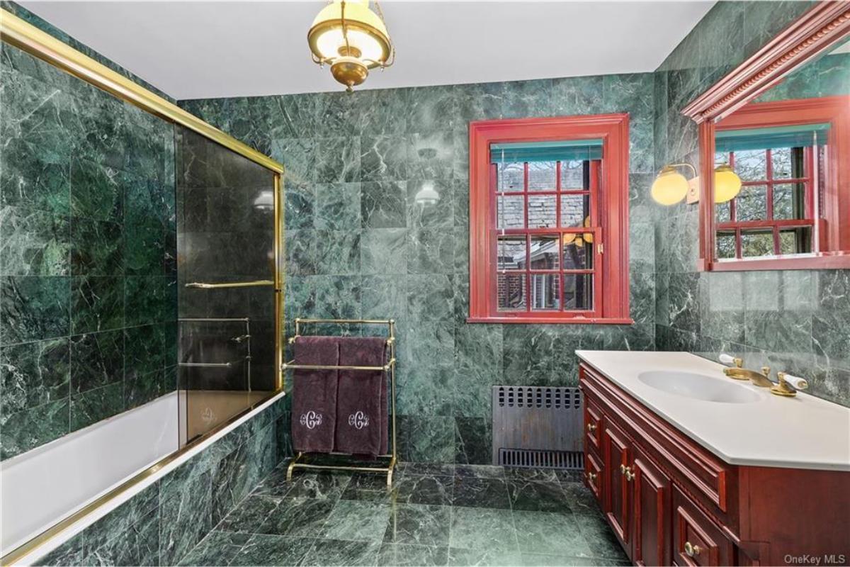 Rich Green Marble Bathroom with Bold Red Trim and Gold Accents