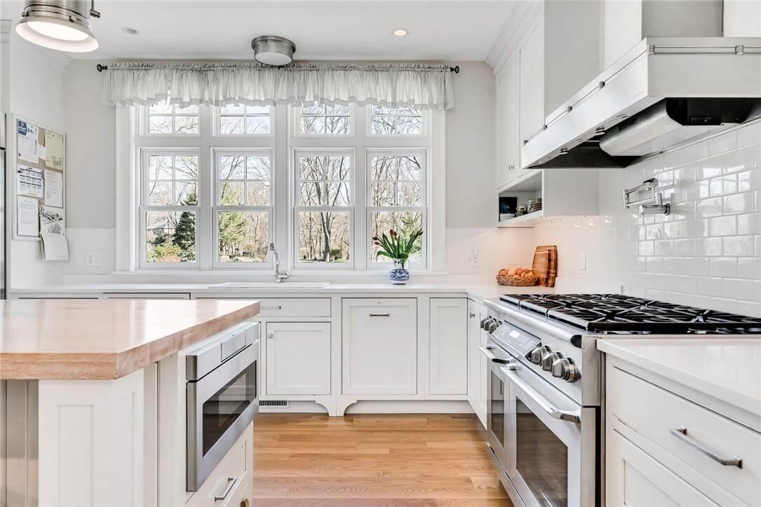 Enjoy the Sleek Gas Range and Hardwood Accents in This Bright Kitchen