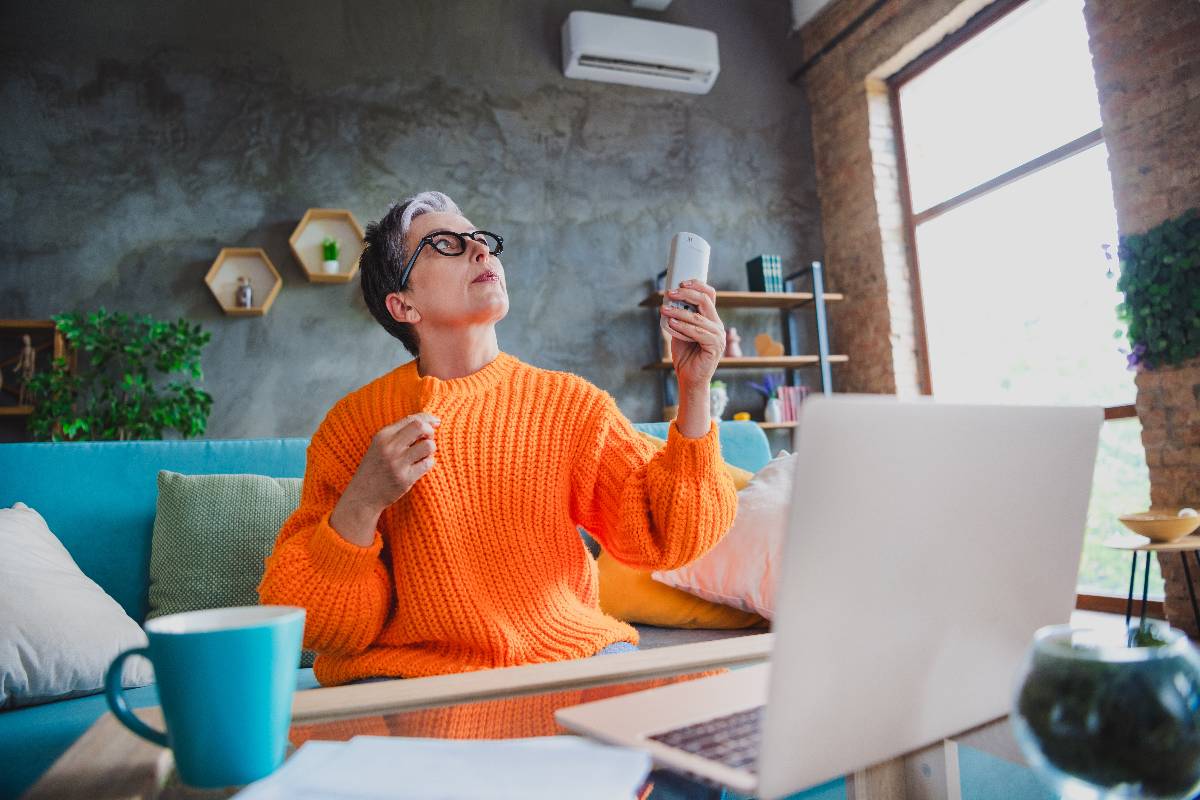 Woman turning on the air conditioner in the living space. 