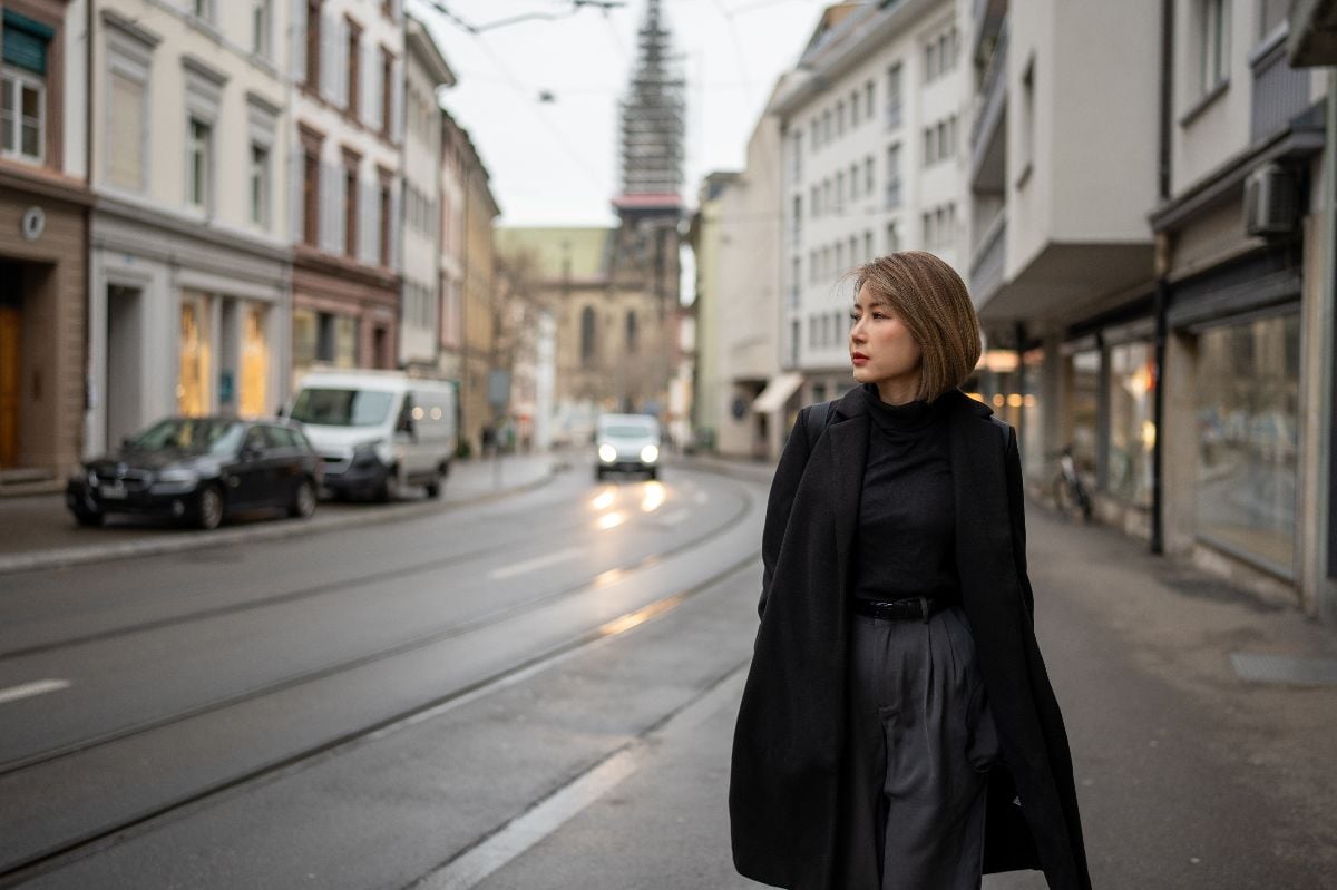 Woman in all black winter coat outfits on the street.