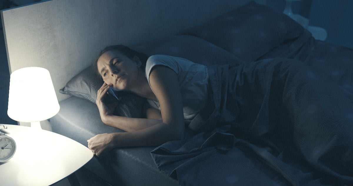 Woman receiving a phone call on her smartphone in the middle of the night.