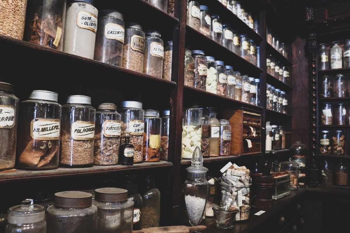 Vintage apothecary interior with glass jars filled with authentic ingredients lining antique shelves.