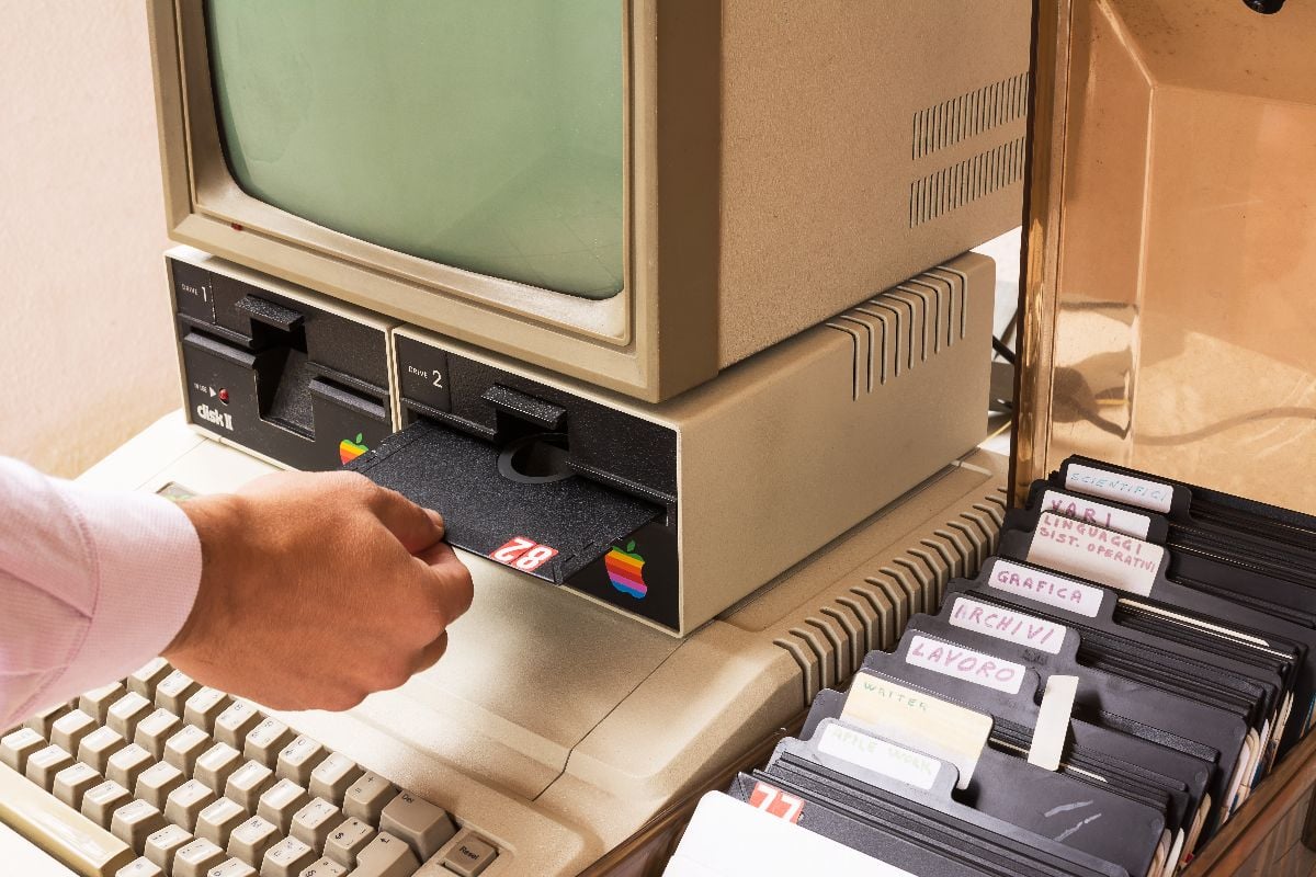 Vintage Apple computer and hand insert floppy drive.