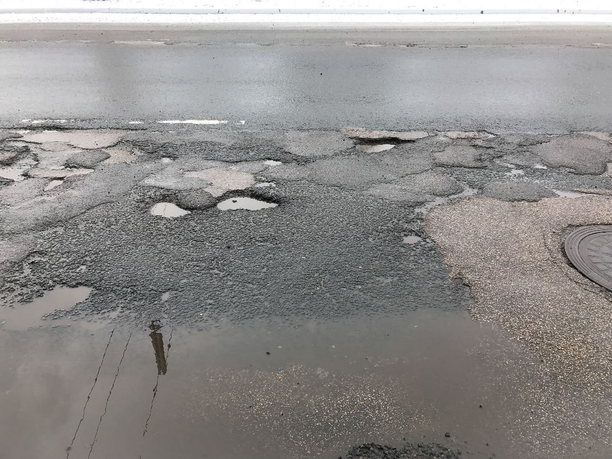 Damaged asphalt road with potholes.