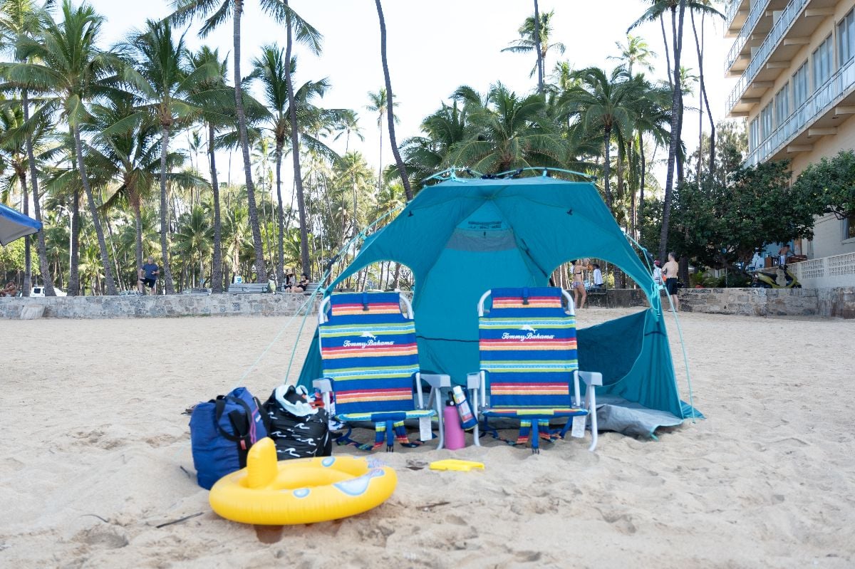 Beach campsite with chairs, umbrella, and toys.