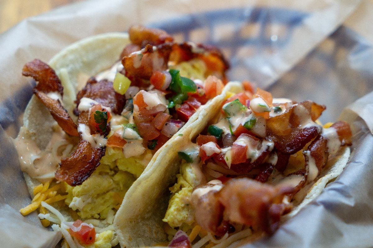 Two breakfast tacos with bacon and eggs.