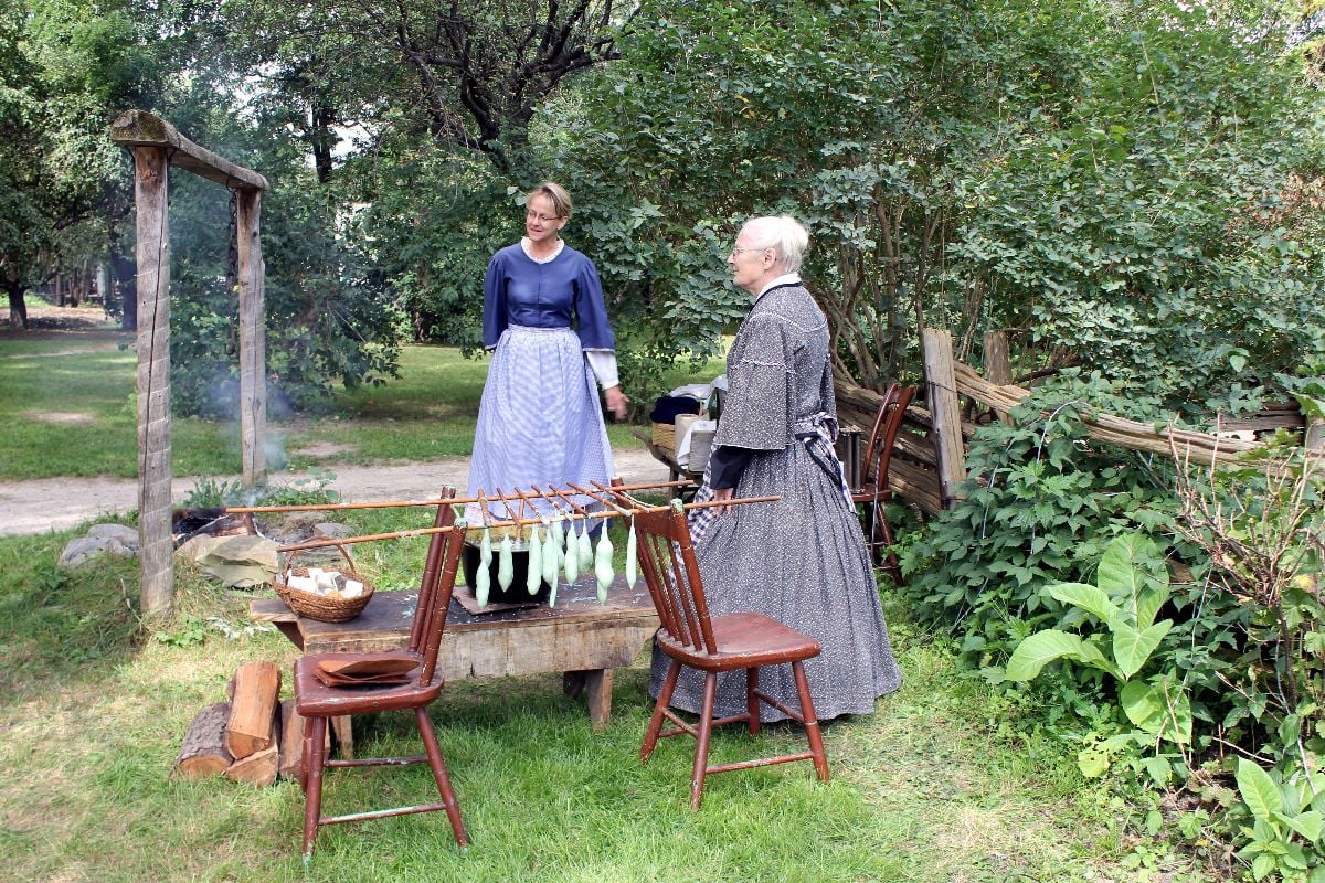 Two women making candles outdoors.