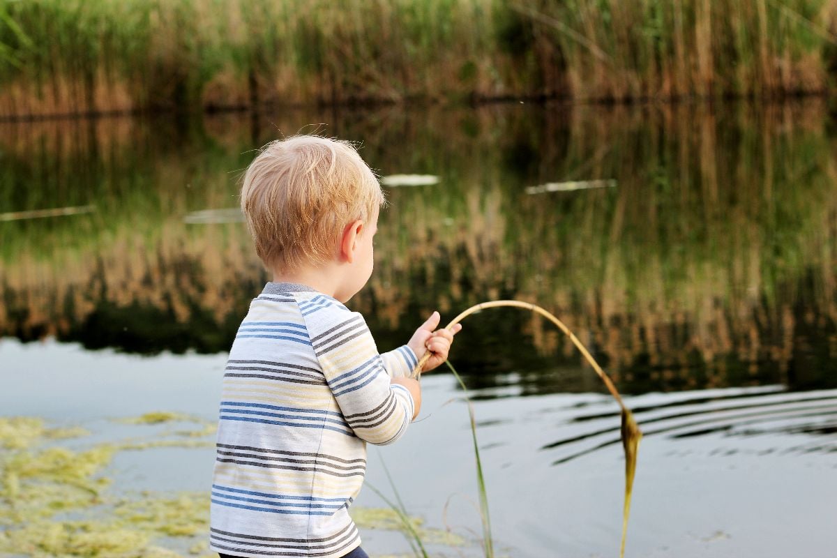 A boy fishing using cane pole.