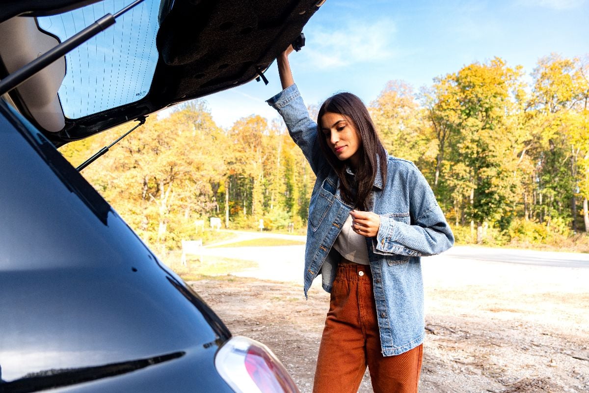 A woman looking inside the open car trunk and checking her items before closing it.