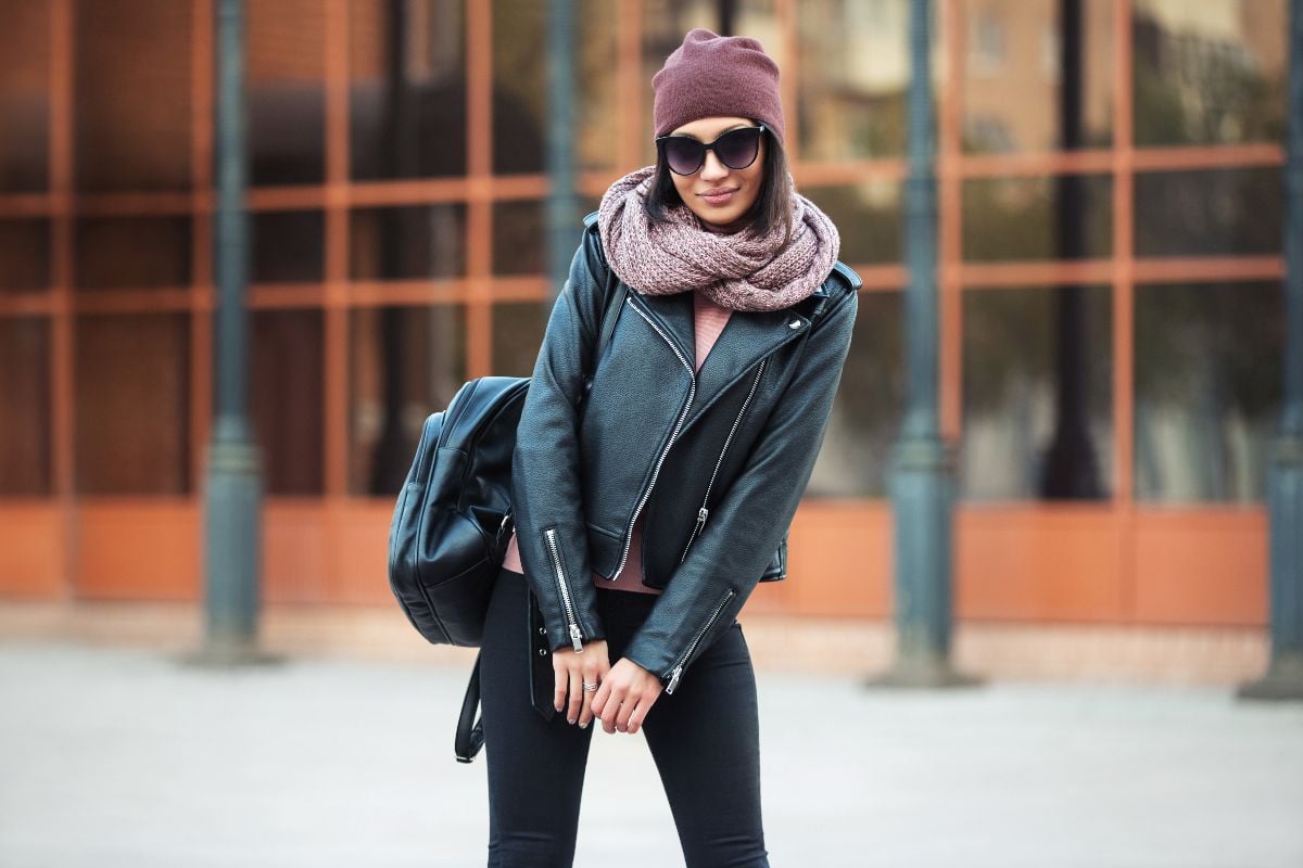 Young woman with backpack walking on city street.