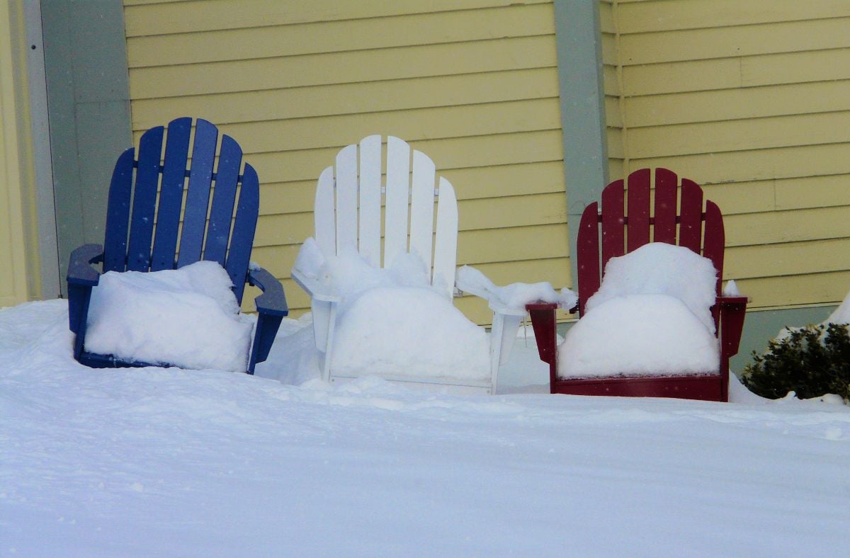 Red, white and blue Andriondack chairs in the snow.