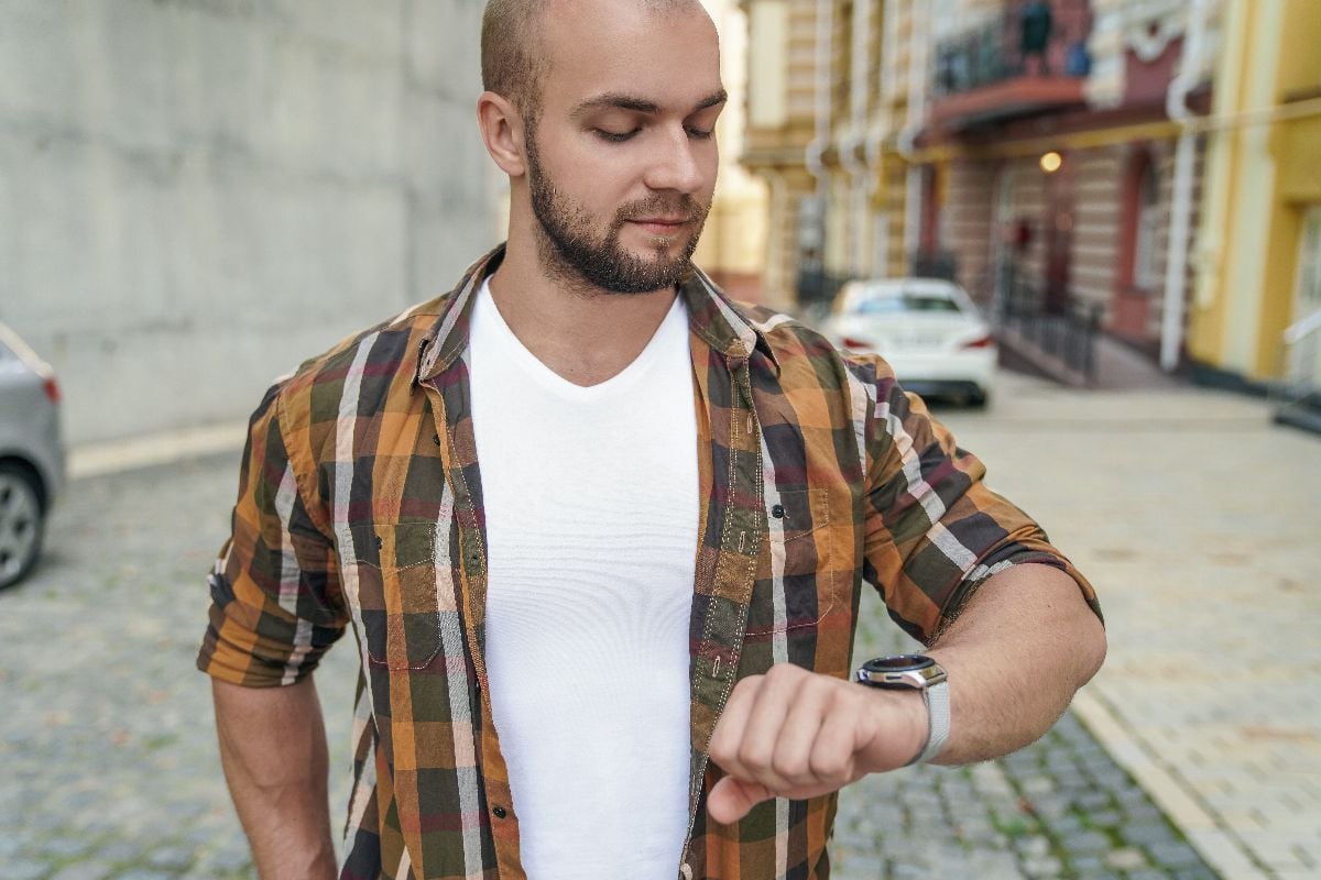 Man checking on his watch outdoors.