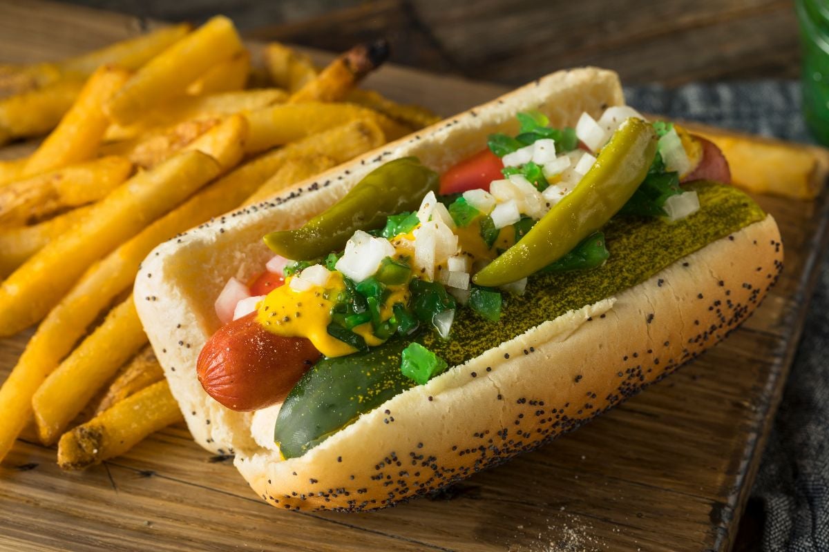 Homemade Chicago-style hotdog with mustard, pickles, tomato, and peppers.