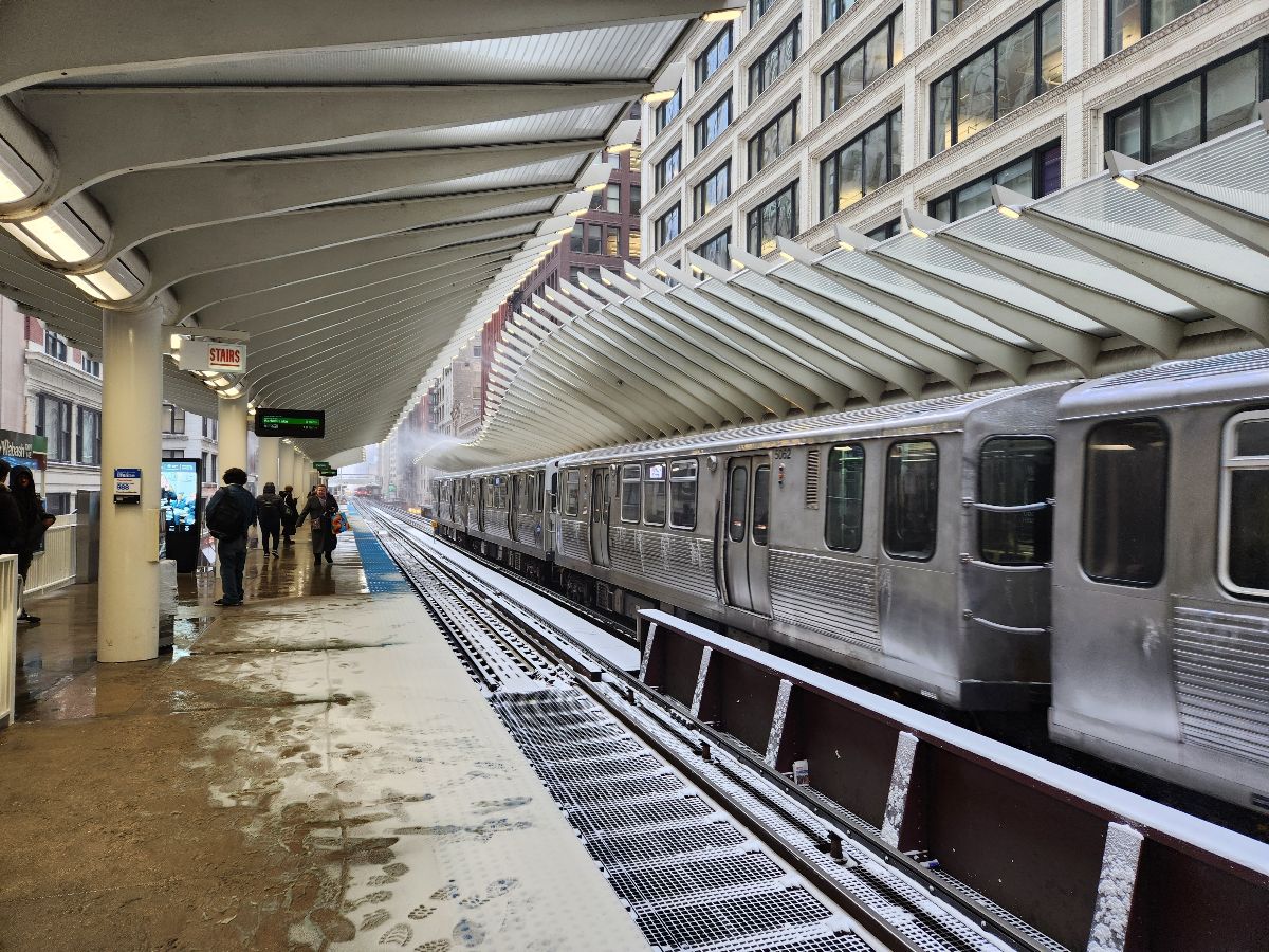 CTA elevated train station with a train entering the station during a winter snowstorm.