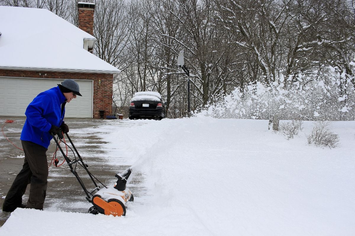 Man clearing his driveway with a snowblower.