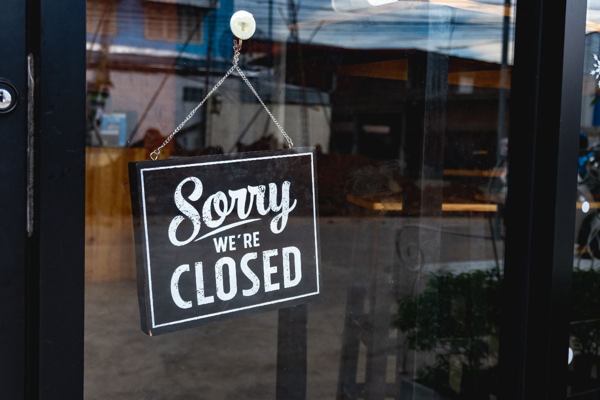 "Sorry we're closed" sign board on a glass door.