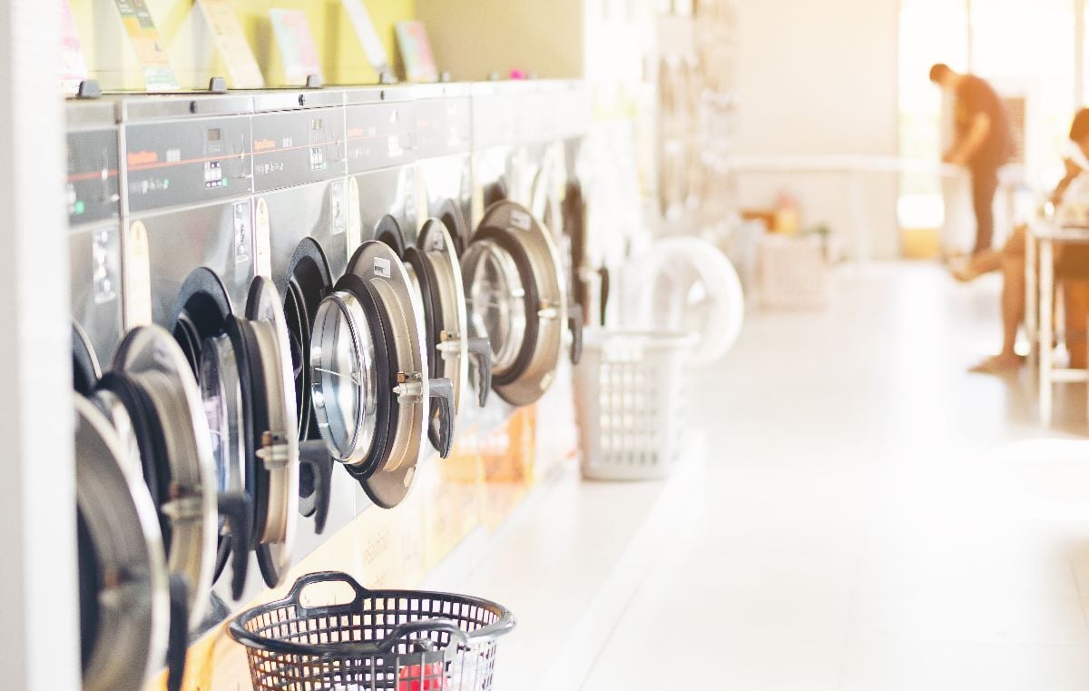 Row of industrial laundry machines in laundromat.