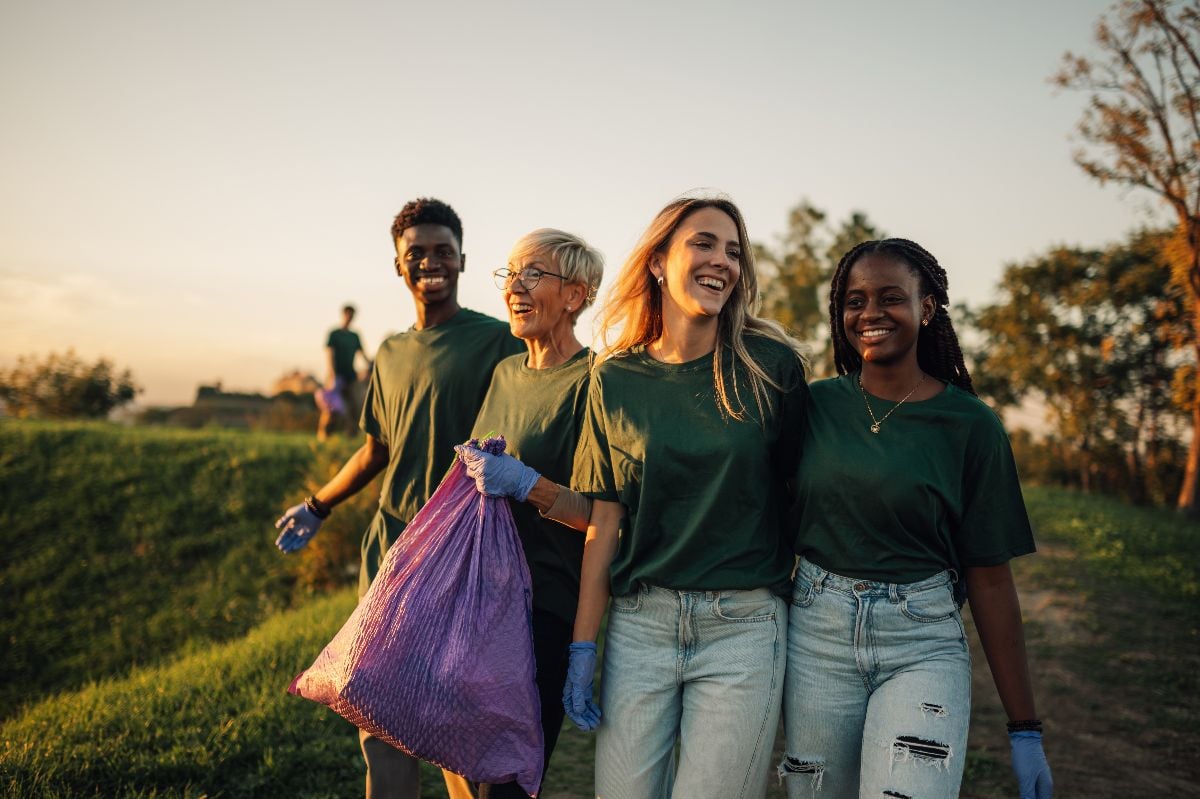 Neighbors carrying garbage bags during a cleanup event in a park.