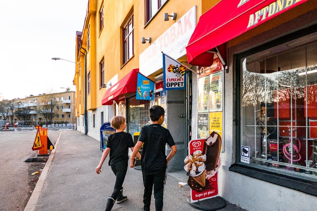 Two boys walking in step to a corner store .