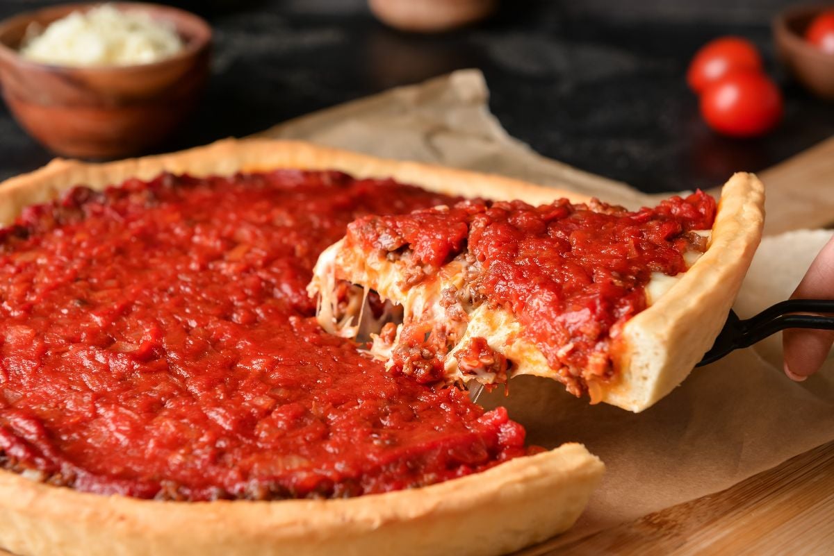 Woman taking a piece of Chicago-style pizza.