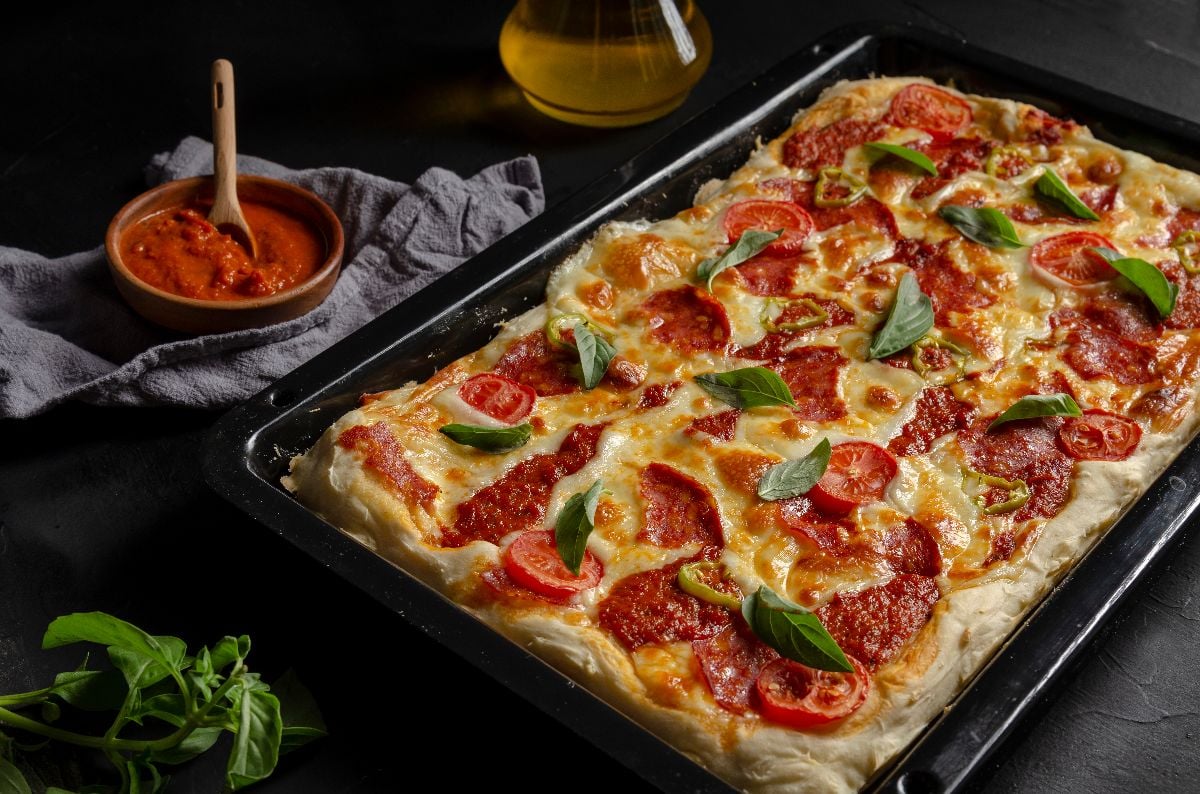 Detroit-style pizza with sauce and garnish on the sides.
