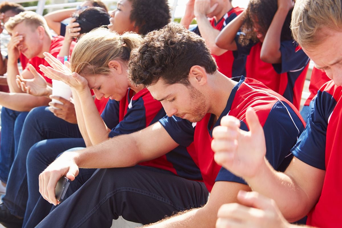 Disappointed spectators in team colors watching sports event.