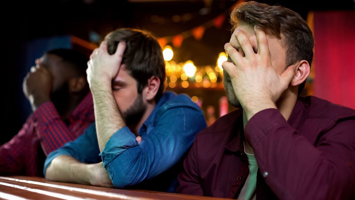 Football fans making facepalm, disappointed with game loss at the bar.