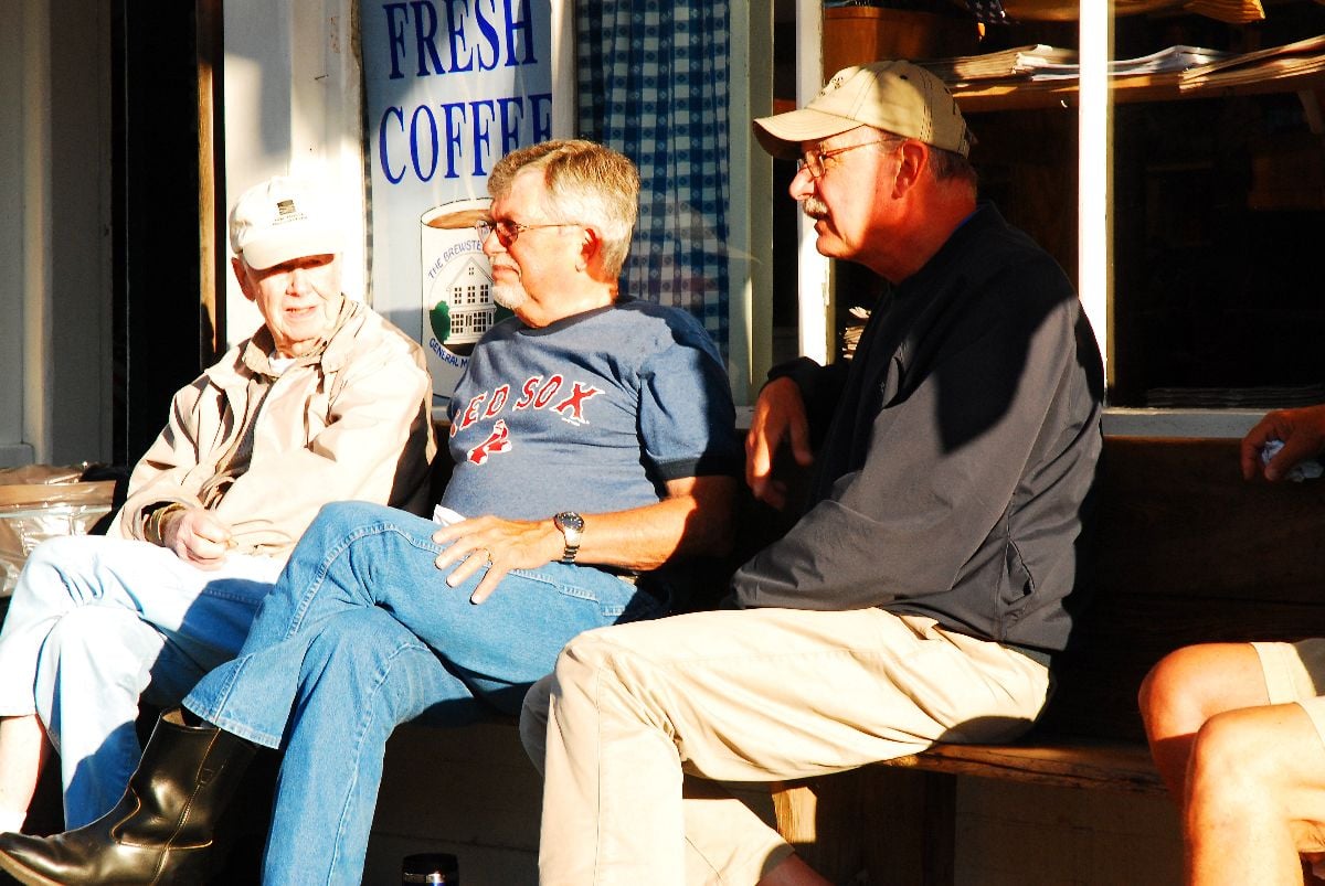 Three elderly men chatting outside the store.