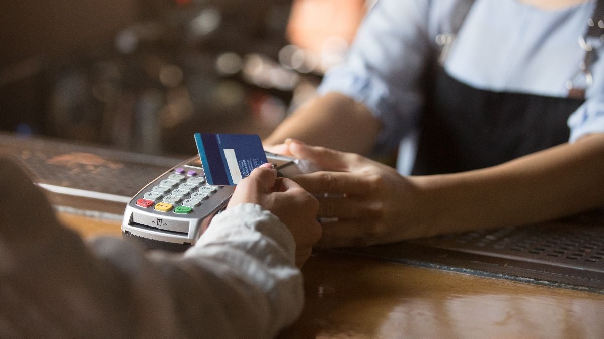 Customer holding credit card near terminal.