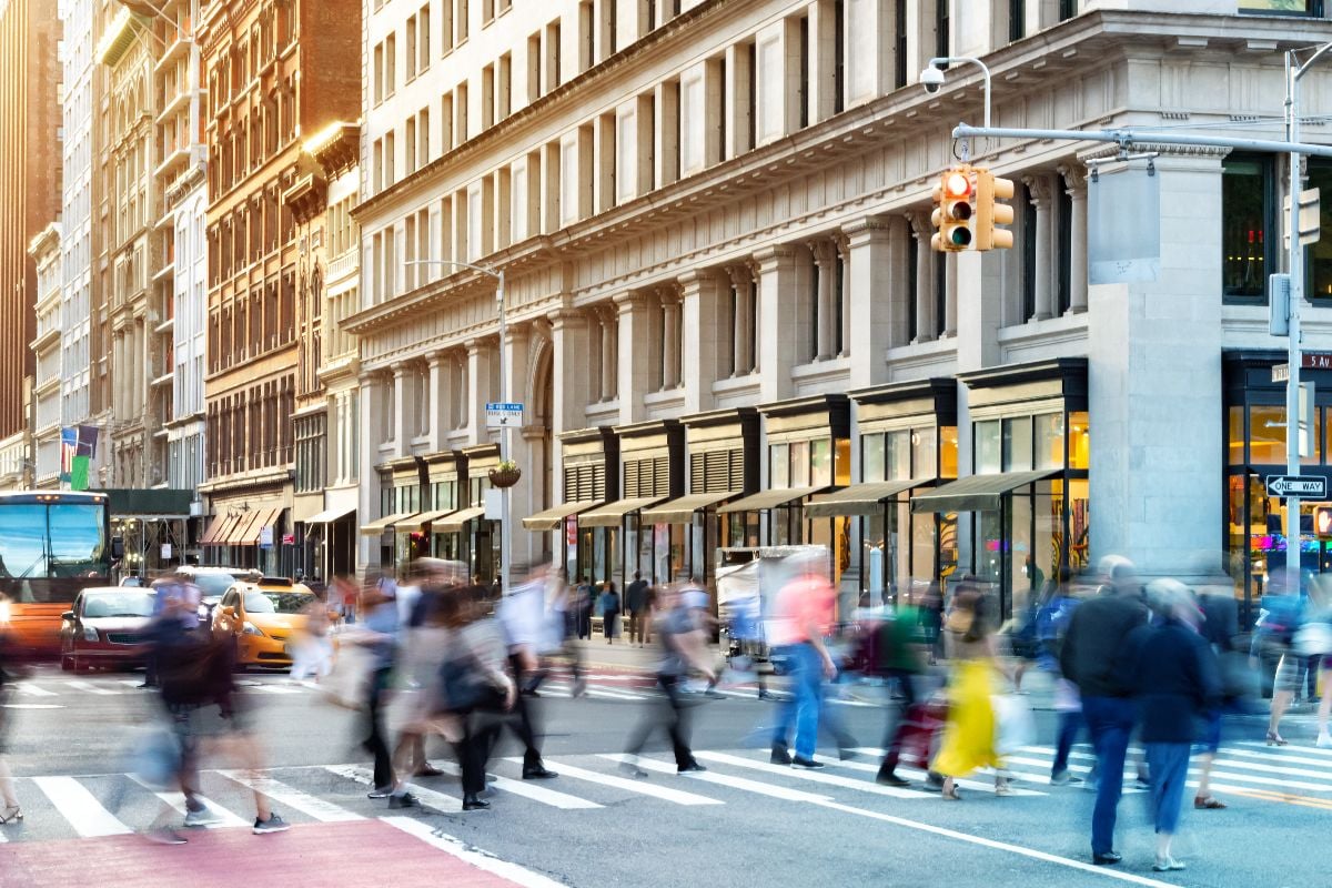 New York City street scene with crowds of diverse people in motion through a busy intersection.